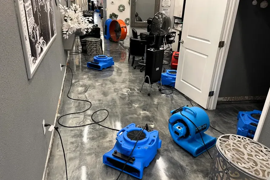 Blue air movers drying a wet hallway floor during a dry out