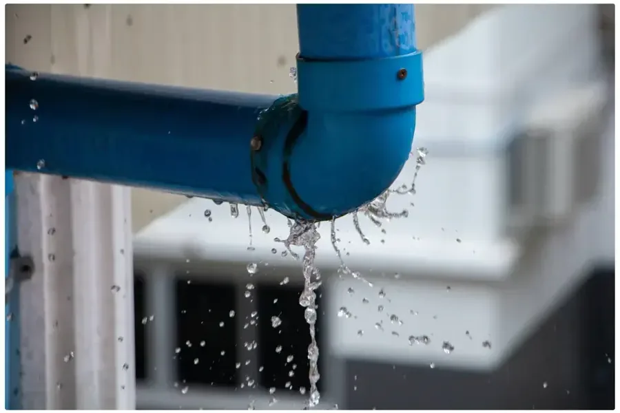 Water spraying from a leaking pipe elbow inside a home