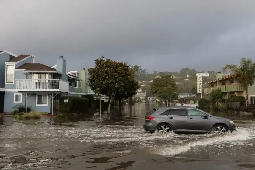 A car driving through storm runoff on a flooded residential street